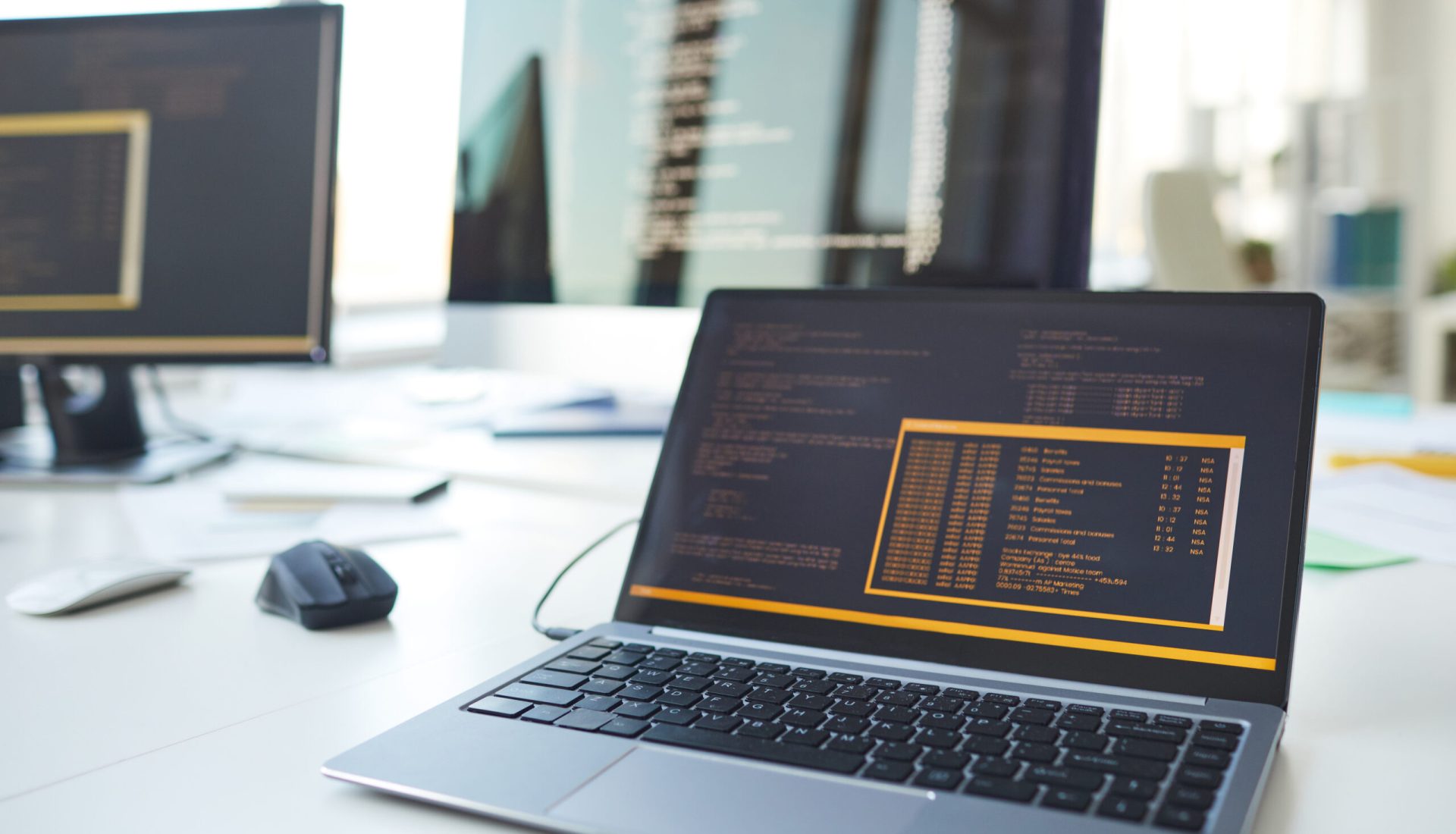 Background image of open laptop with code on screen at desk in IT developers office, copy space